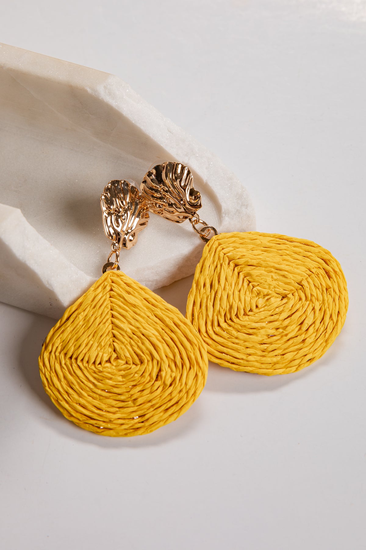 Yellow textured earrings with gold accents on a light background