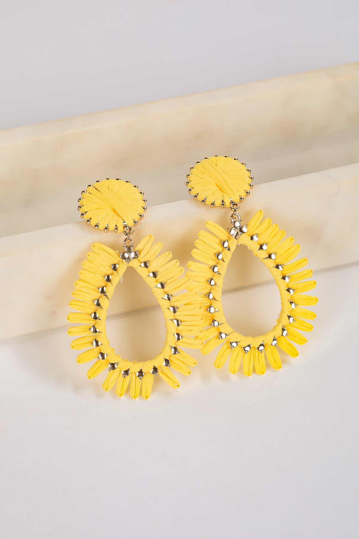 Yellow earrings with circular design on a light background