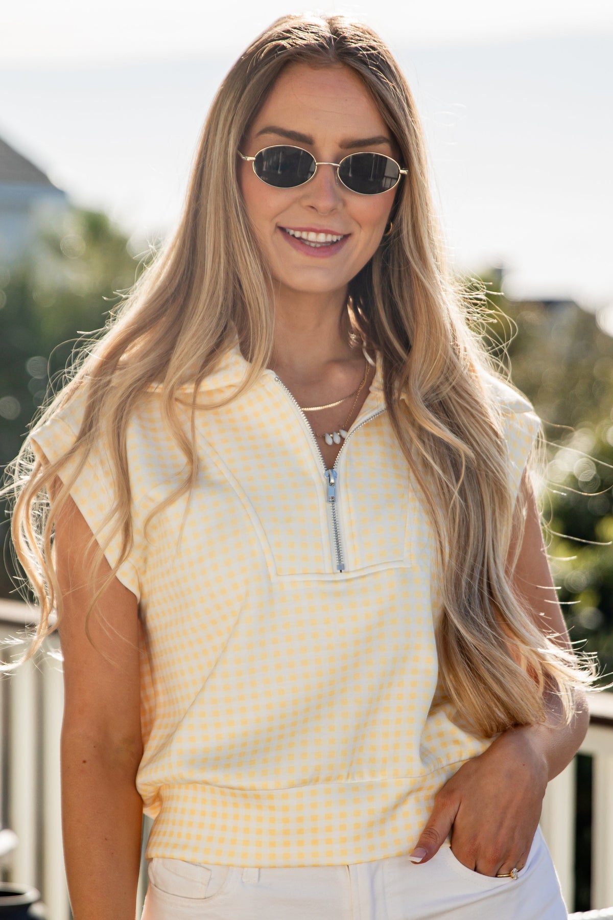 woman wearing a yellow gingham quarter zip collared tank top
